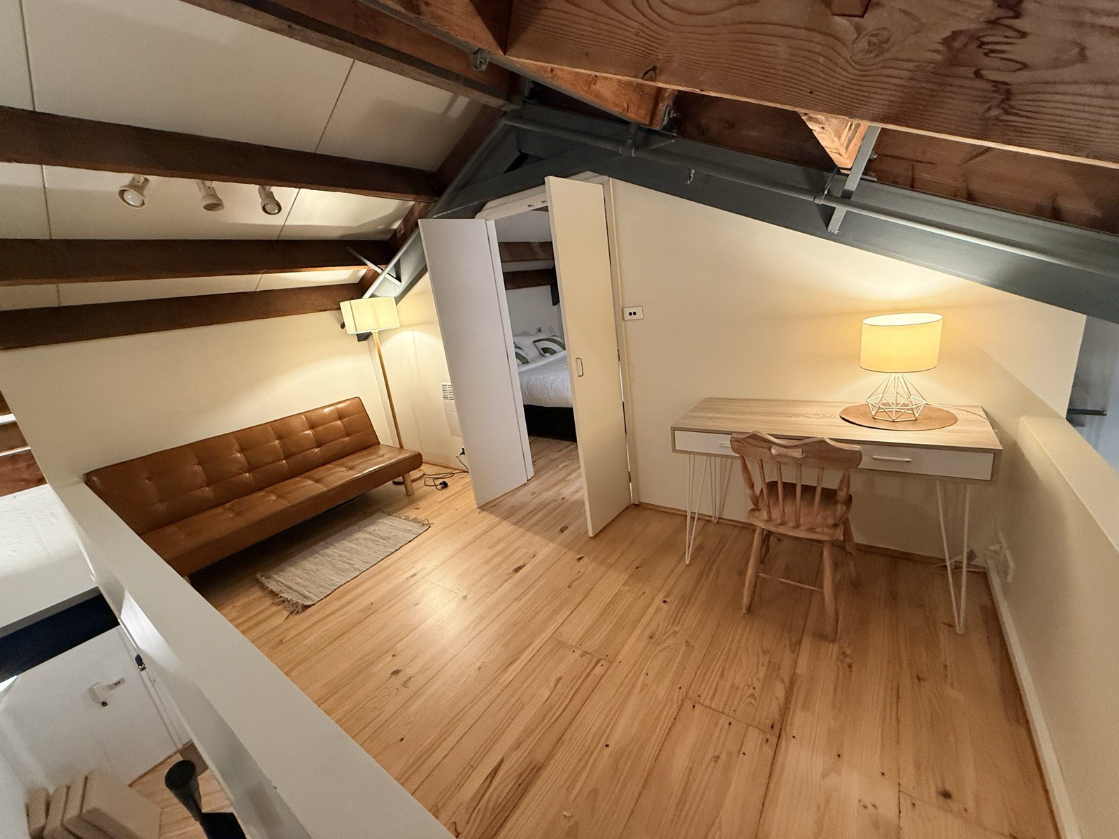 The mezzanine sleeping area with a fold-out sofa bed, beside a glimpse of the bedroom