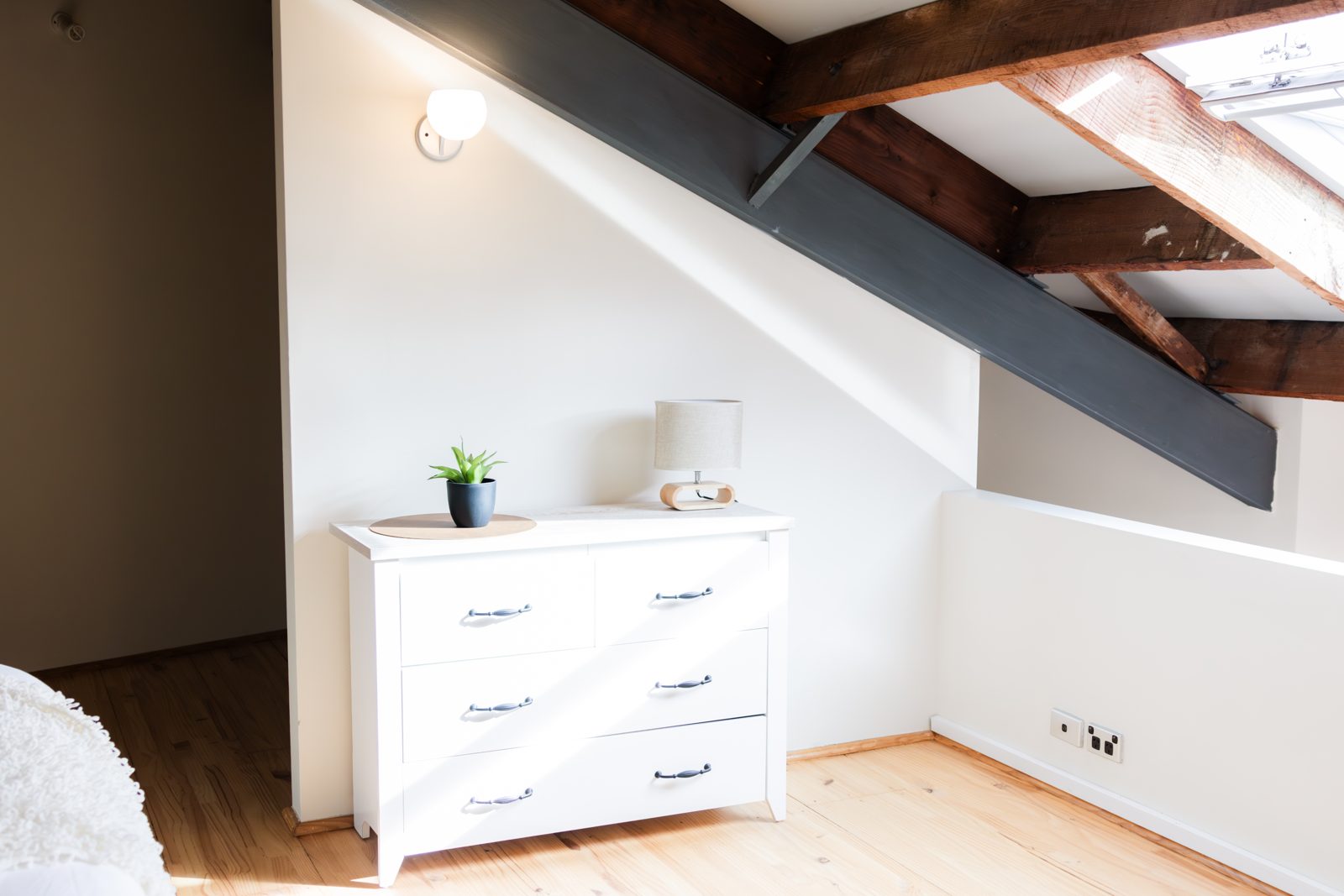 The bedroom with white drawers tucked under the timber-beamed eaves