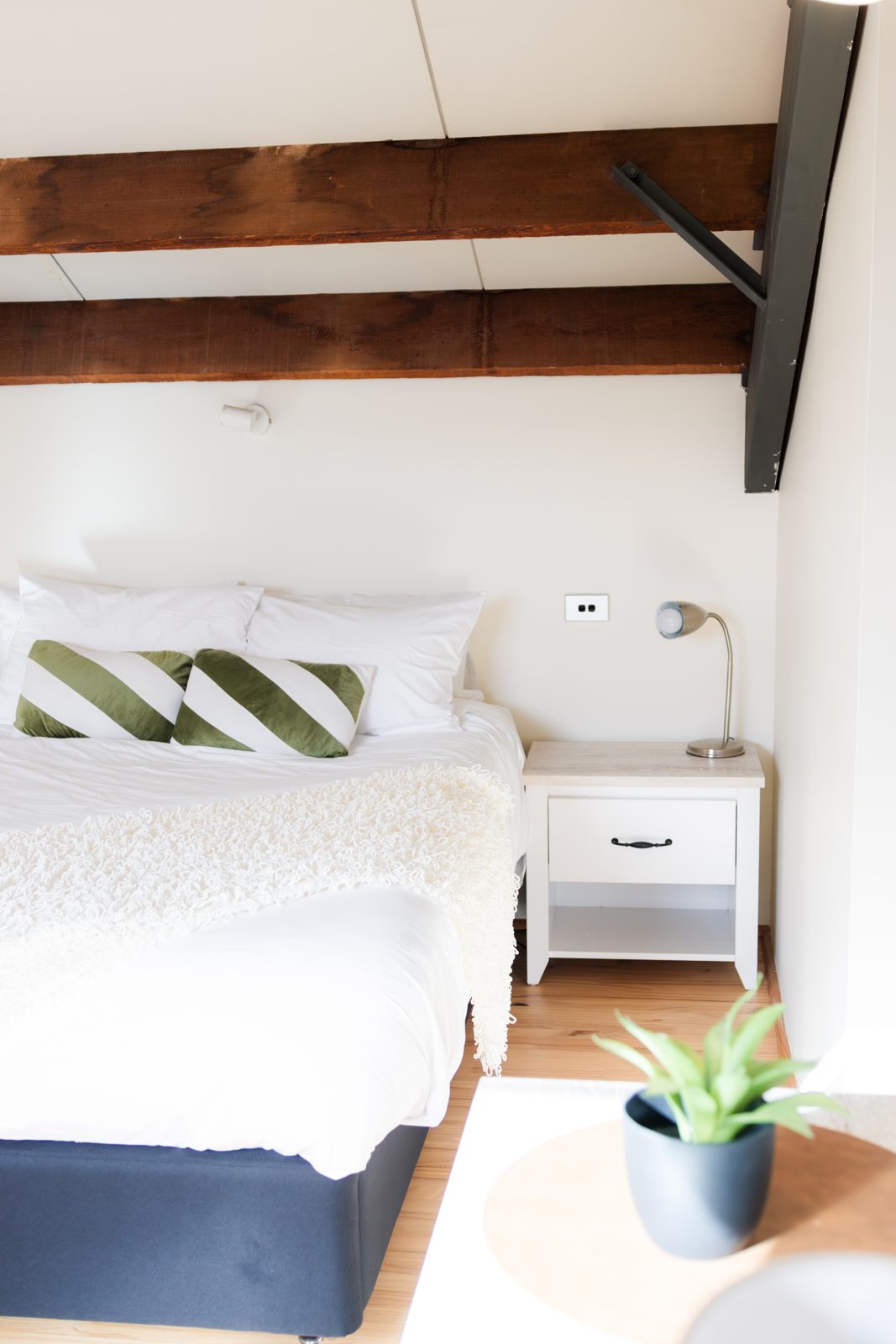 The bed dressed in crisp white linen beneath the loft's timber beams