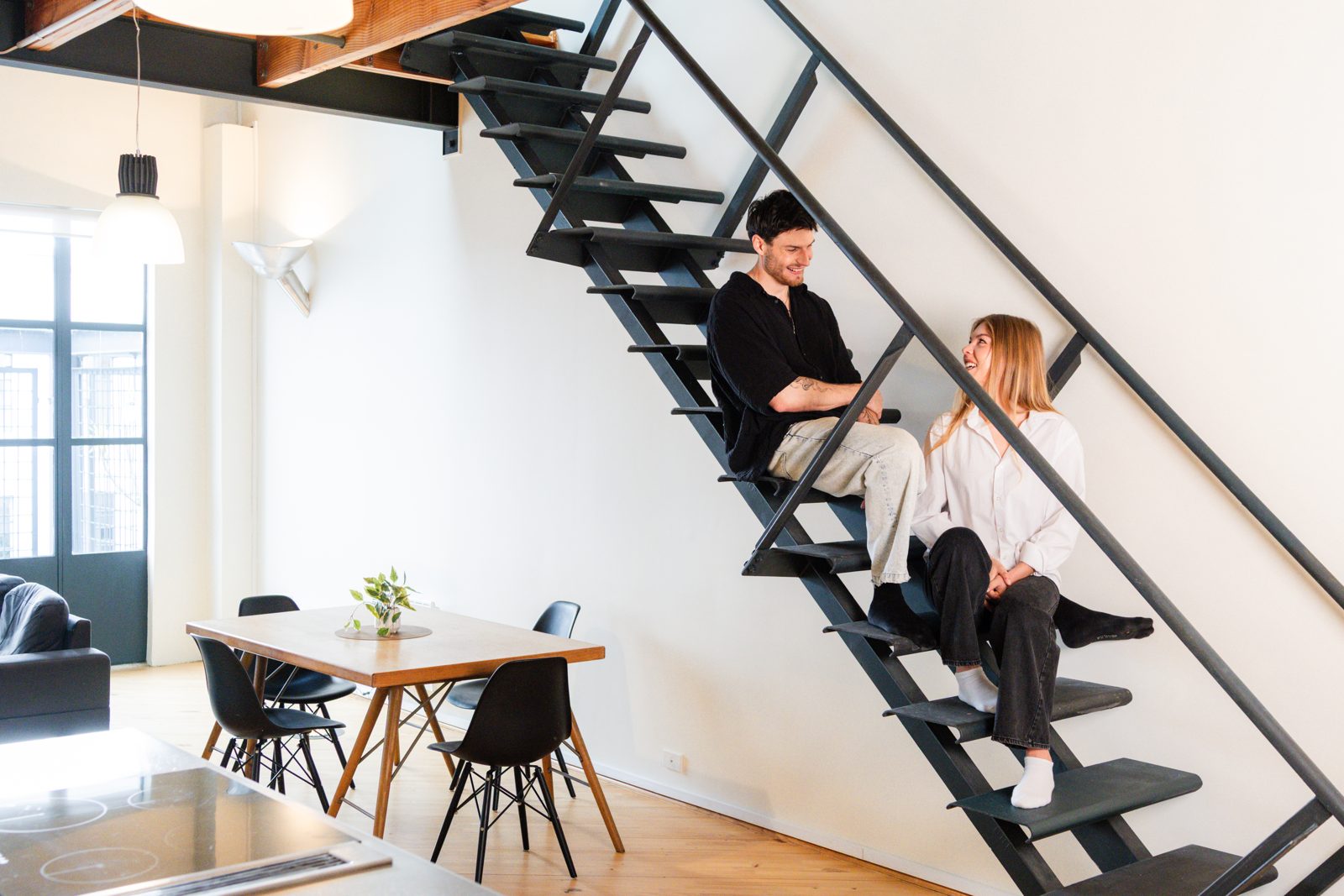 The double-height living space with the black steel staircase and dining area