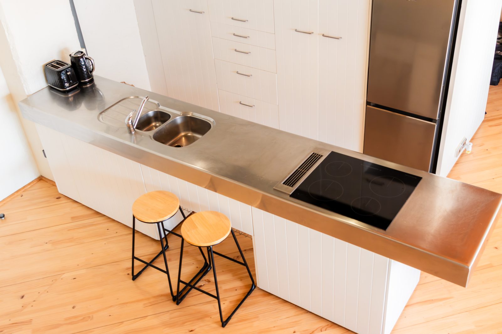 The full kitchen with stainless counter and timber stools